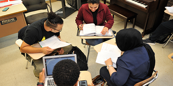 A group of four students working together in a classroom.